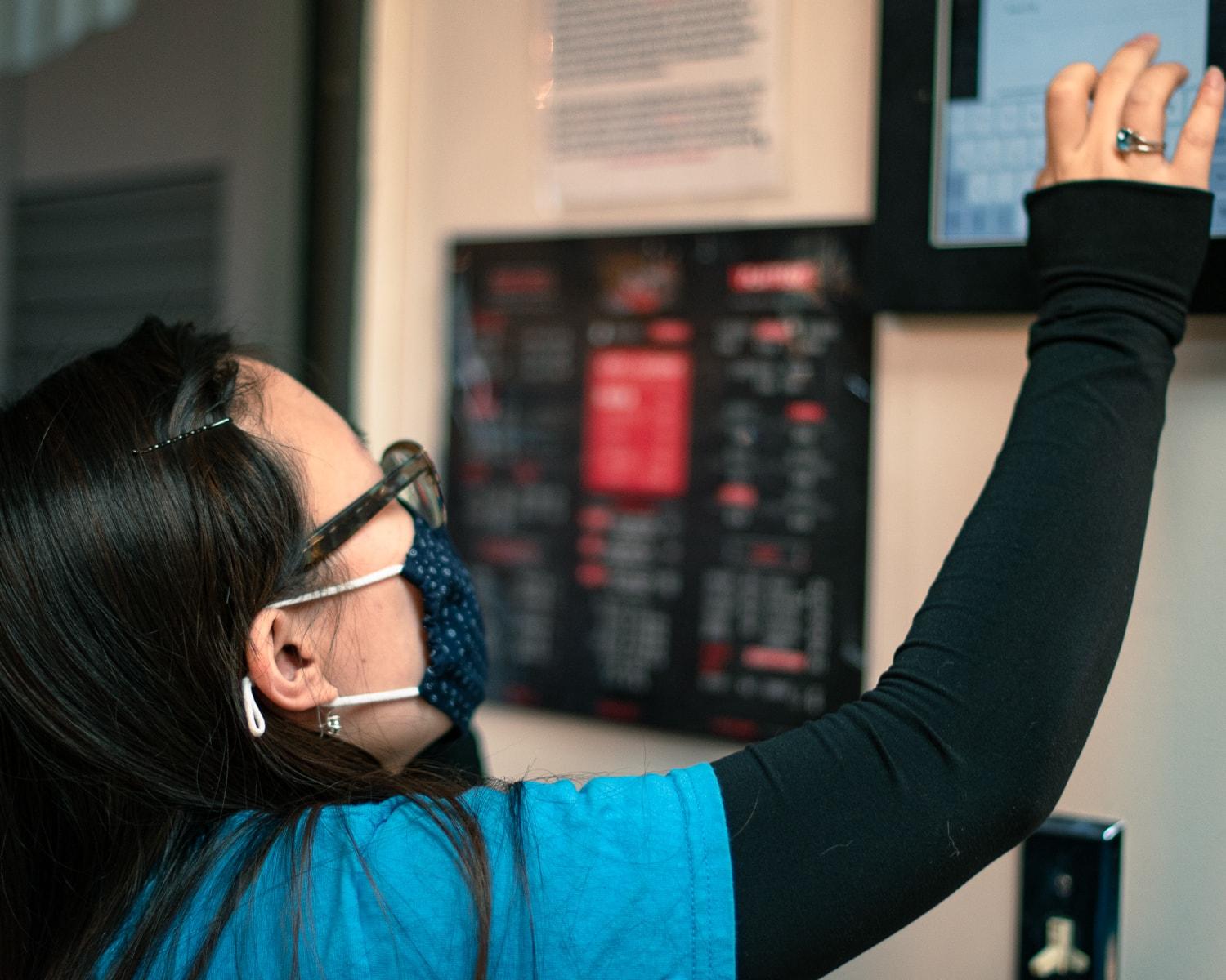 A Fatbacks BBQ team member taking an order on the wall-mounted Square tablet, with the menu board behind her.